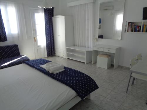 a white bedroom with a bed and a desk at Blue and White Studios & Apartments in Lefkos Karpathou