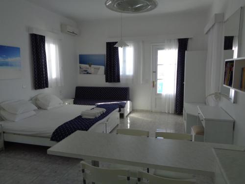 a white living room with a couch and a table at Blue and White Studios & Apartments in Lefkos Karpathou