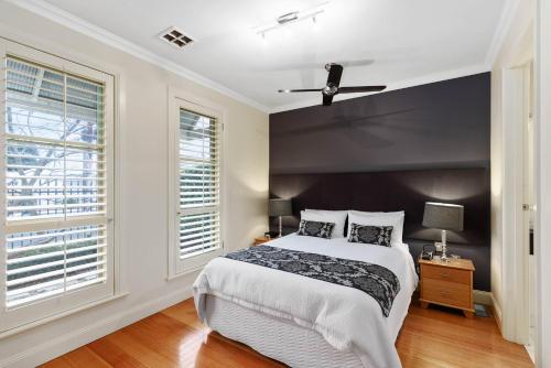 a bedroom with a large bed and two windows at Domain One Apartment in Mount Gambier