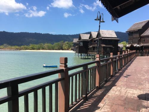 a bridge over a body of water with houses and a boat at Langkawi Lagoon Resort Water Chalet in Pantai Cenang