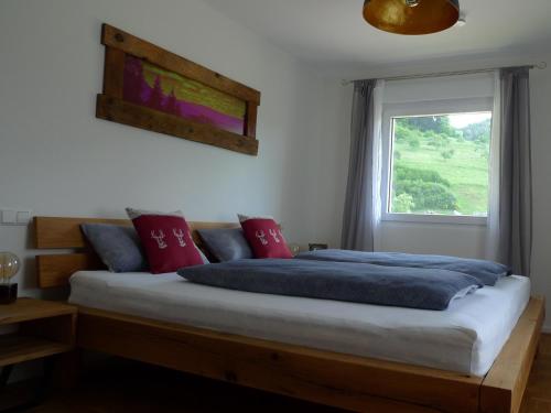 een slaapkamer met een bed met rode kussens en een raam bij Ferienwohnung Schwarzwald-Traum in Haslach im Kinzigtal