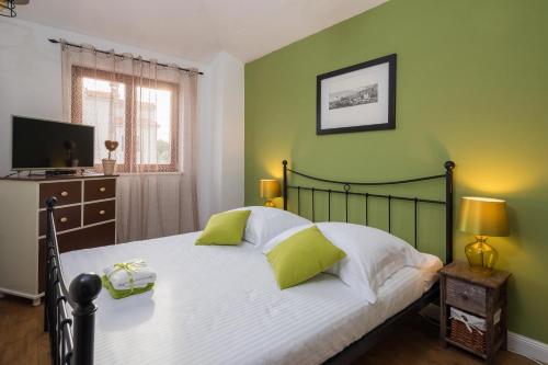 a bedroom with a large bed with green walls at Villa Sunshine in Rogoznica