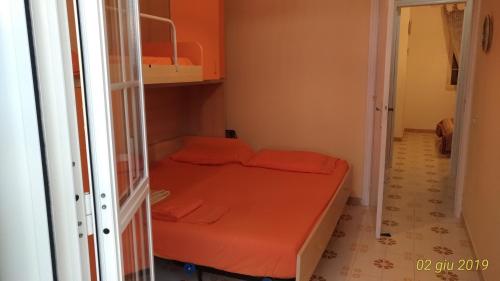 a small room with a bed with orange sheets at Villetta Carati in Torre dell'Orso