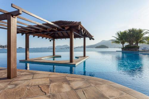 a swimming pool with a gazebo next to the water at Hotel Nacional Inn Angra dos Reis in Angra dos Reis