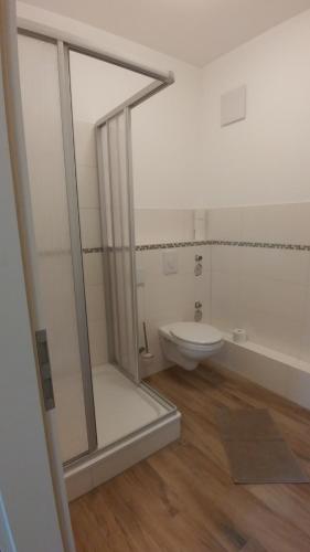 a white bathroom with a shower and a toilet at Mirabellenhof - Kleine Ferienwohnung mit Altstadtblick in Biesenthal