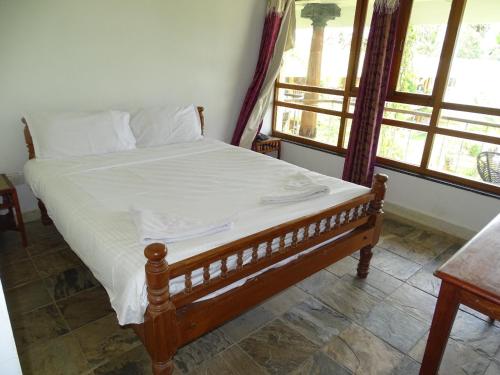 a bedroom with a bed with white sheets and a window at Nalla Eco Beach Resort in Pondicherry