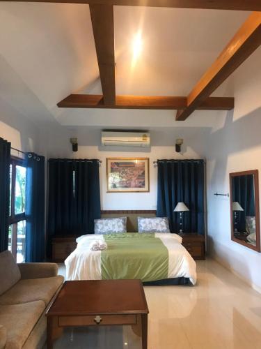 a bedroom with a bed and a couch at Damnoen Care Resort in Damnoen Saduak