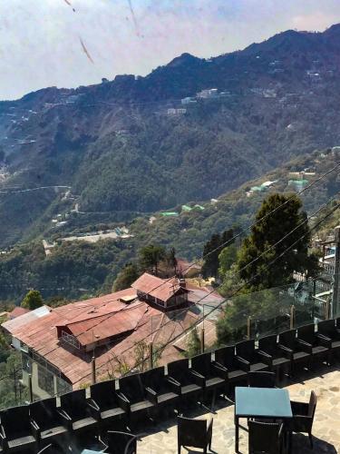 a view of a building with chairs and a mountain at The Fern Brentwood Resort, Mussoorie in Mussoorie