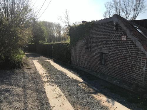 a brick wall next to a road next to a building at Poortbossen in Zottegem