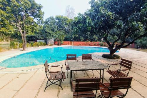 a table and chairs in front of a swimming pool at Serenity Corbett Resort in Garjia