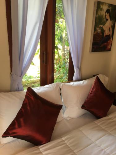 a bed with red and white pillows in front of a window at Naraya Homestay in San Pa Tong