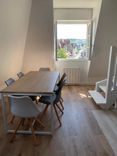 une salle à manger avec une table et des chaises et une fenêtre dans l'établissement Duplex au cœur de Deauville avec vue imprenable et parking privé, à Deauville