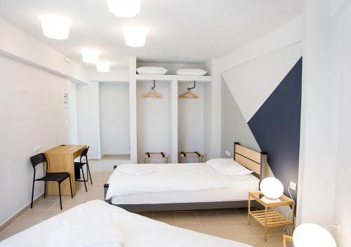 a bedroom with two beds and a table and a desk at Snooze H in Athens