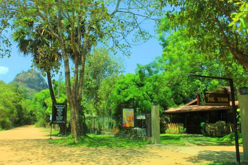 a park with a tree and a building at Thal Sewana in Sigiriya