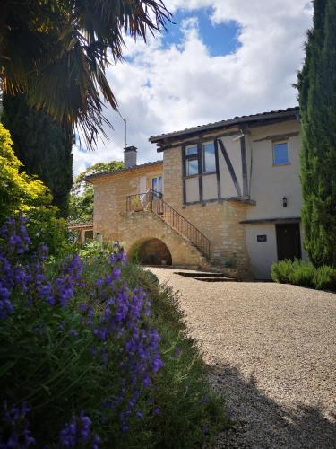 a house with a stone driveway and purple flowers at Castel Mazars in Castelnau-de-Montmiral