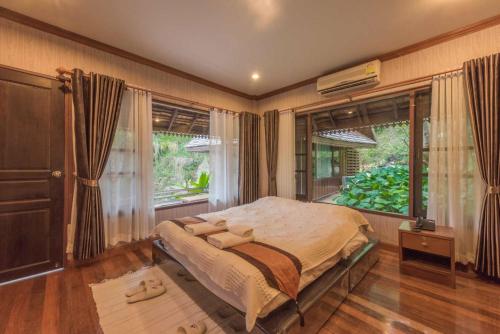 a bedroom with a bed and a large window at Kangsadarn Resort and Waterfall in Pong Yaeng