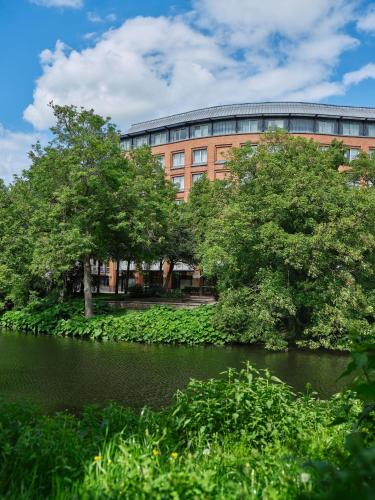 a building in front of a body of water with trees at Dorint Hotel Bremen in Bremen