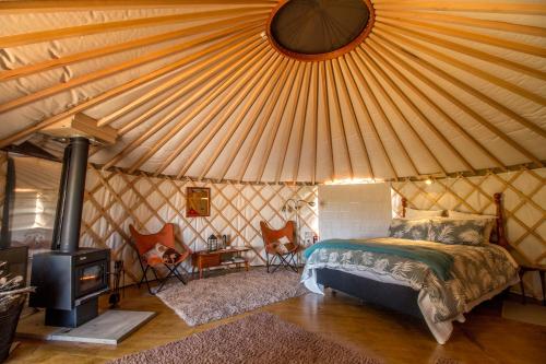 a bedroom in a yurt with a bed and a stove at The Yurt Wai Rua in Whangarei