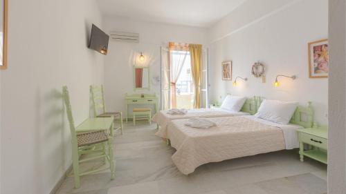a white room with two beds and a tv at Hotel Sphinx in Naxos Chora