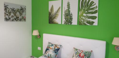a bedroom with green walls and a white bed with pillows at ele&gio accomodation in Tropea