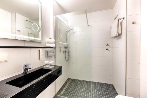 a white bathroom with a sink and a shower at ACHAT Hotel Bad Dürkheim in Bad Dürkheim