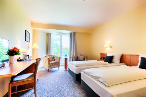 a hotel room with two beds and a desk at ACHAT Hotel Bad Dürkheim in Bad Dürkheim