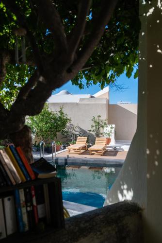 a swimming pool with two chairs and a book shelf at Kalitsi Canaves in Vóthon