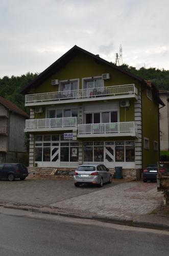 a yellow building with a car parked in front of it at Apartments Sokolović in Višegrad