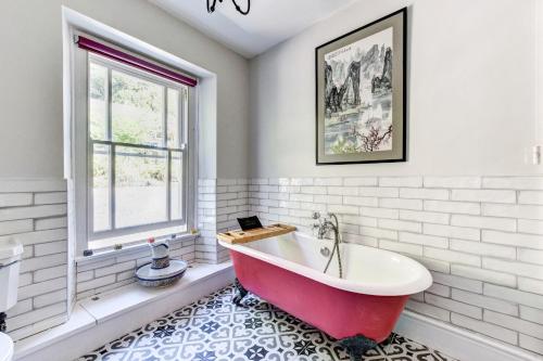 a bathroom with a red tub and a window at Bwthyn y Bardd in Llanstephan