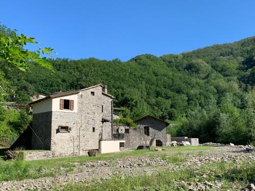 an old stone building in a field in front of a mountain at Magic Mill Castagnetoli in Mulazzo