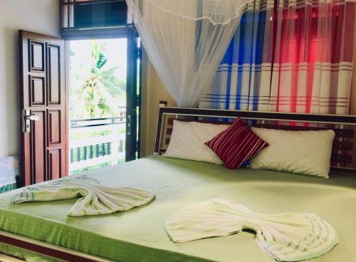 a bed with two towels on it with a window at Amaya Gate in Matara