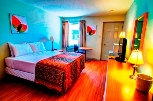 - une chambre avec un lit, une table et une télévision dans l'établissement Wescana Inn, à Le Pas