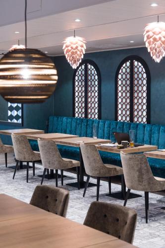 a row of tables and chairs in a restaurant with blue walls at Hotel Verso in Jyväskylä