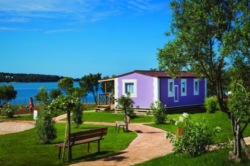 a small house in a park with a bench at Premium Sirena Village Mobile Homes in Novigrad Istria