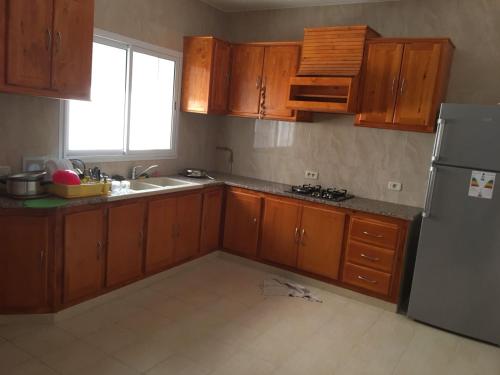 a kitchen with wooden cabinets and a stainless steel refrigerator at Belle Vue de Mer in Tazarka