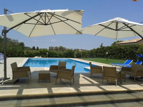 a patio with chairs and umbrellas next to a pool at Hotel Villa Aurora in Latina