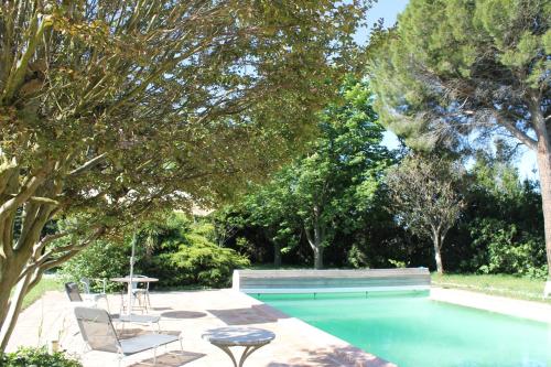 - une piscine avec des chaises, une table et des arbres dans l'établissement Le Mas des Figuiers, à Arles
