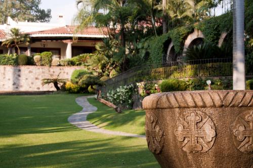 a stone vase with a cross on it in a yard at Las Mañanitas in Cuernavaca