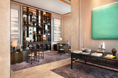a lobby of a hotel with a man sitting at a desk at Raffles Shenzhen, Situated in the heart of One Shenzhen Bay, Book Now to Enjoy Free Minibar and Happy Hour Privileges at Long Bar on 71F in Shenzhen