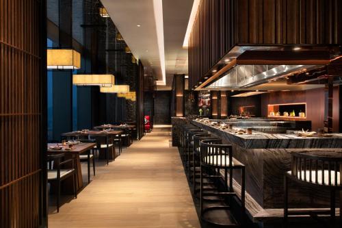 a restaurant with a long line of tables and chairs at Raffles Shenzhen, Situated in the heart of One Shenzhen Bay, Book Now to Enjoy Free Minibar and Happy Hour Privileges at Long Bar on 71F in Shenzhen