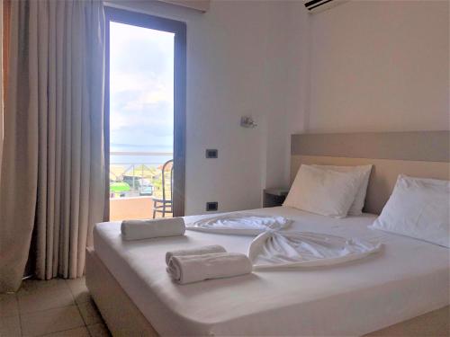 1 dormitorio con 1 cama con 2 toallas en JB Hotel, en Sarandë