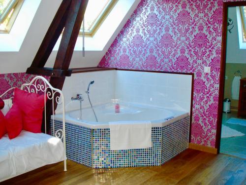 ein Bad mit einer Badewanne in einem Zimmer mit rosafarbener Tapete in der Unterkunft Chateau de la Vallee, Normandy in Grandcourt