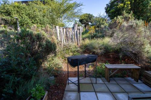 a grill and a wooden table in a garden at Nature's Cottage in Kenton on Sea
