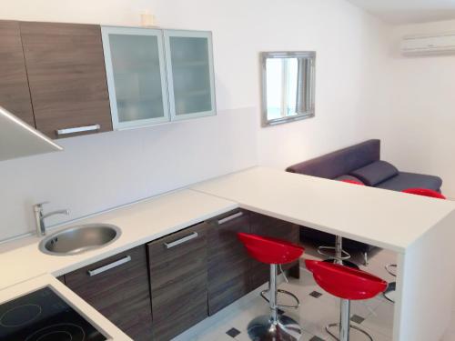 a kitchen with a sink and red stools at Apartment Cesarica in Cesarica