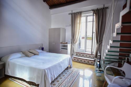 a white bedroom with a bed and a staircase at Rooms 19 B&B in Palermo