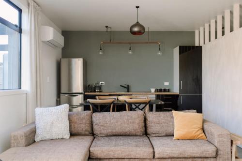 a living room with a couch and a kitchen at Three Streams Raglan Retreat in Raglan