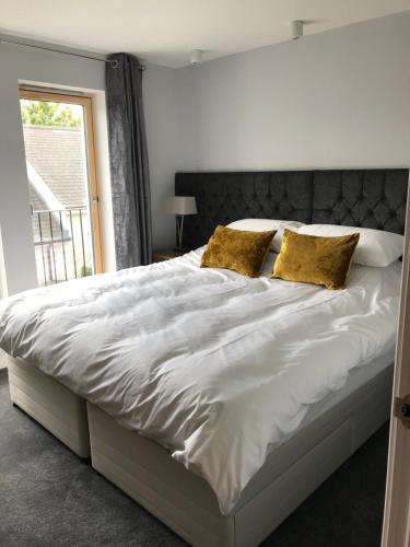 a bedroom with a large white bed with gold pillows at Apt 2, Frasers Close in Kirkwall