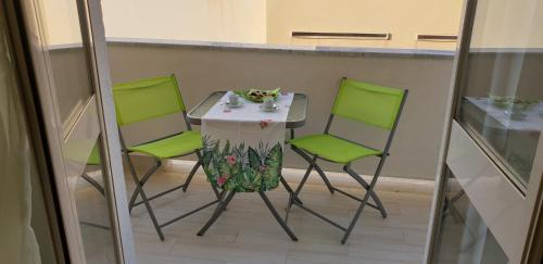 a table and two green chairs sitting on a balcony at ele&gio accomodation in Tropea