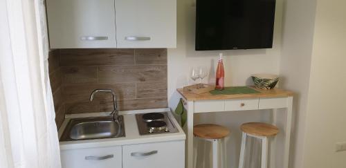 a small kitchen with a sink and a counter with stools at ele&gio accomodation in Tropea