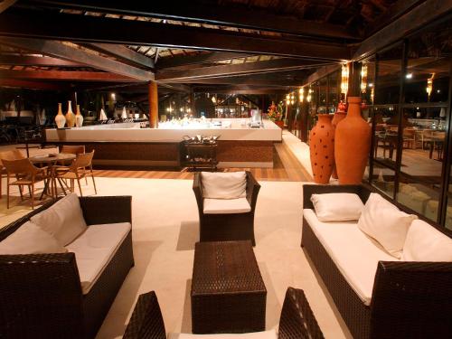 a restaurant with couches and a table and chairs at Serrambi Resort in Porto De Galinhas